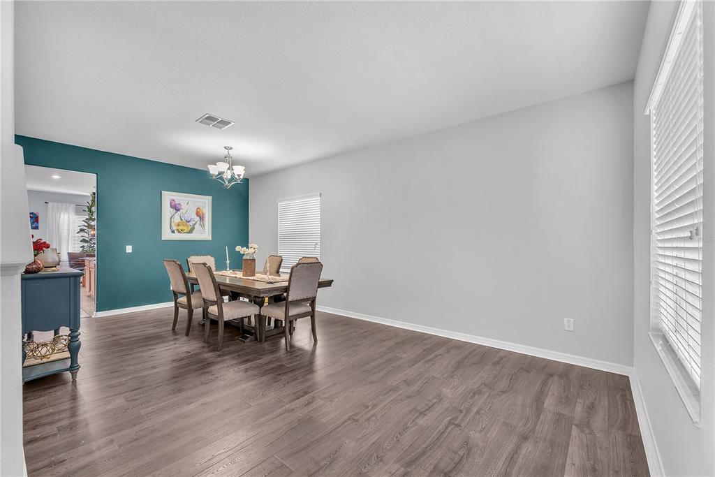 A dining room with wood-look flooring, a teal accent wall, and a rectangular dining table — 10921 RAINBOW PYRITE DRIVE, WIMAUMA, FL
