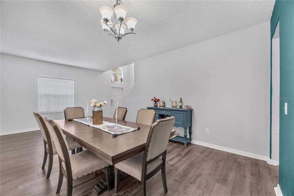A dining room features a wooden table with six chairs, a blue sideboard, and laminate flooring — 10921 RAINBOW PYRITE DRIVE, WIMAUMA, FL