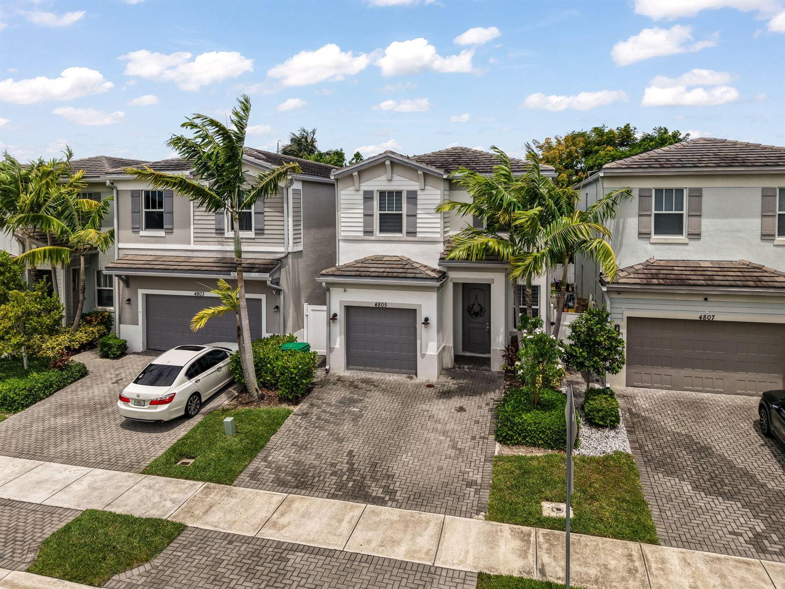 Three two-story suburban houses with gray garages and palm trees stand along a paved street — 4805 NW 48th Terrace, Tamarac FL 33319, TAMARAC, FL