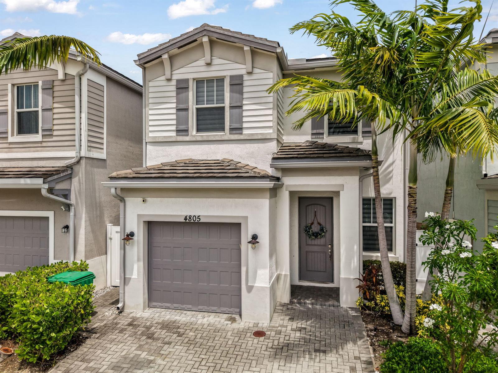 A two-story suburban home features a gray garage door, a front entrance, and palm trees — 4805 NW 48th Terrace, Tamarac FL 33319, TAMARAC, FL