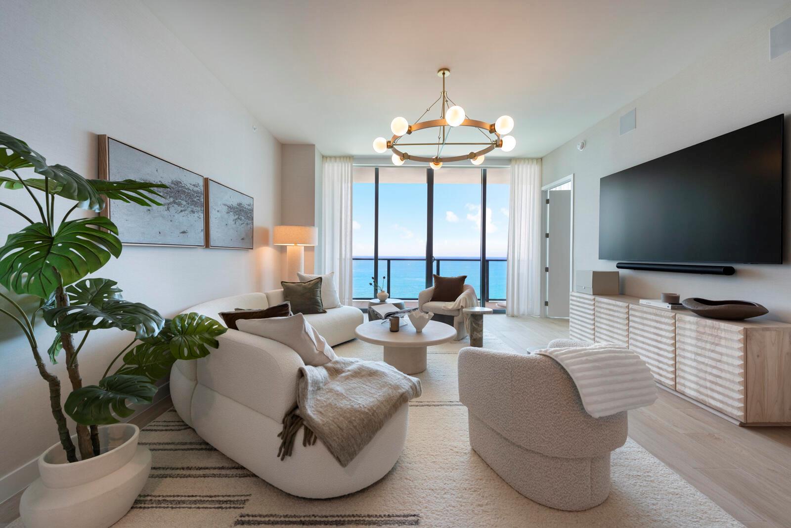 A modern living room features a curved sofa, textured armchairs, and floor-to-ceiling ocean views — 900 N Ocean Boulevard, Pompano Beach FL 33062, POMPANO BEACH, FL
