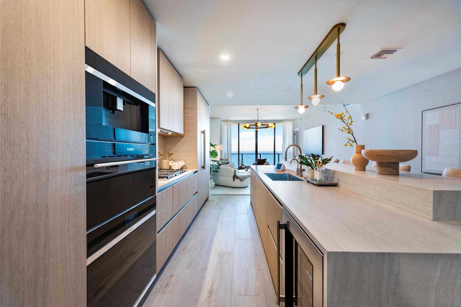A modern kitchen with light wood cabinetry, stone countertops, and an ocean view beyond — 900 N Ocean Boulevard, Pompano Beach FL 33062, POMPANO BEACH, FL