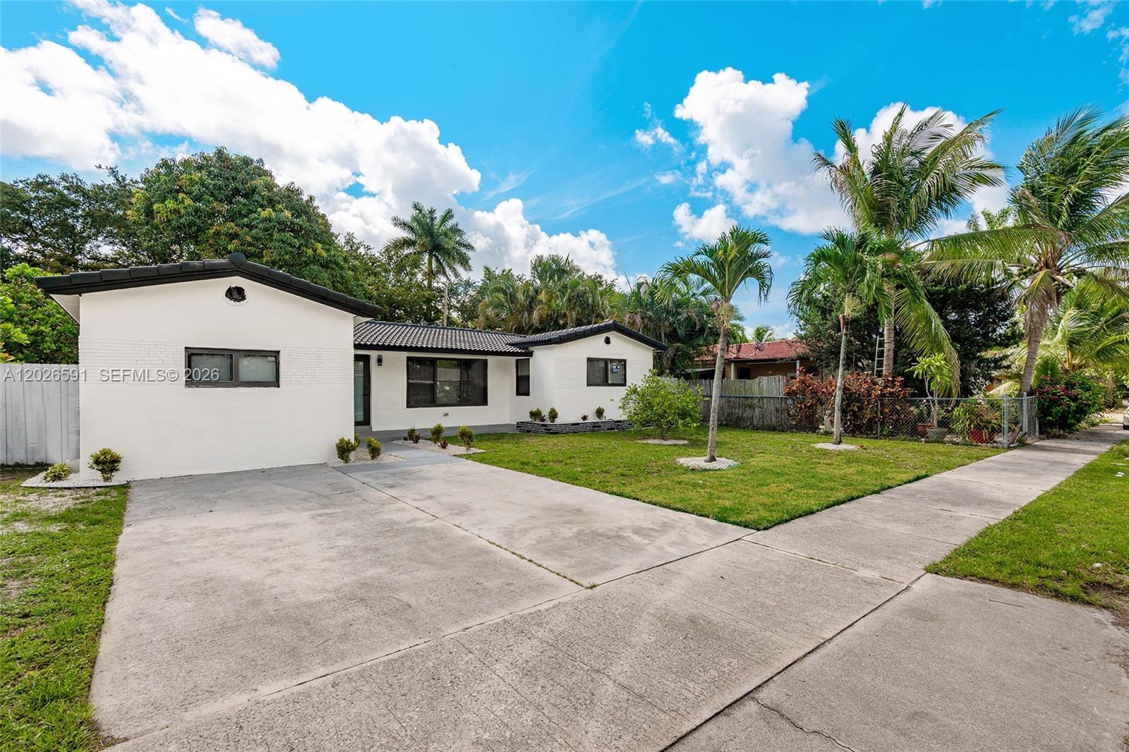 A white, single-story house features a concrete driveway, a front lawn, and several palm trees — 537 S 29th Ct, Hollywood FL 33020, HOLLYWOOD, FL