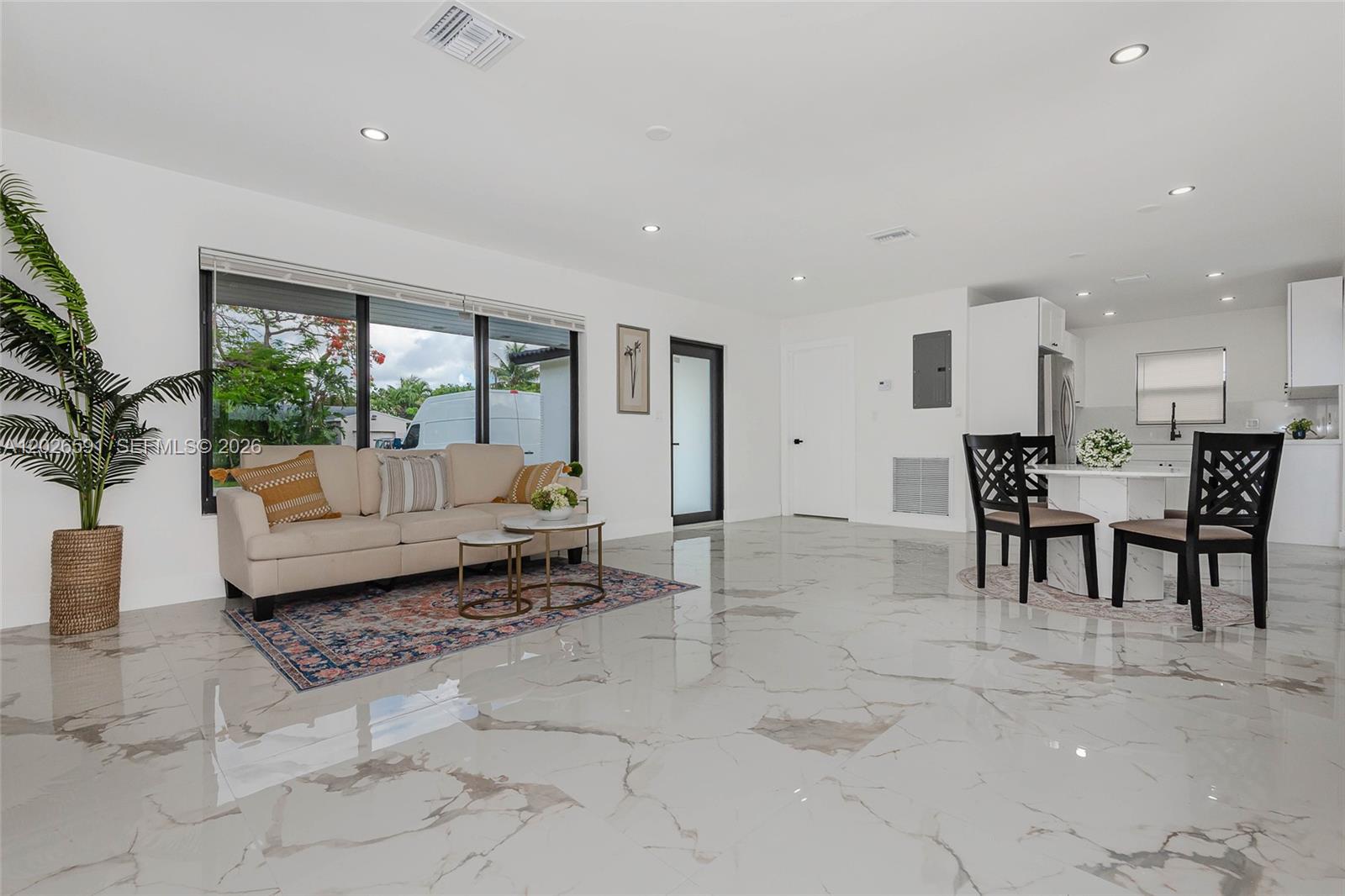 A bright open-concept living and dining area features white marble floors and a beige sofa — 537 S 29th Ct, Hollywood FL 33020, HOLLYWOOD, FL