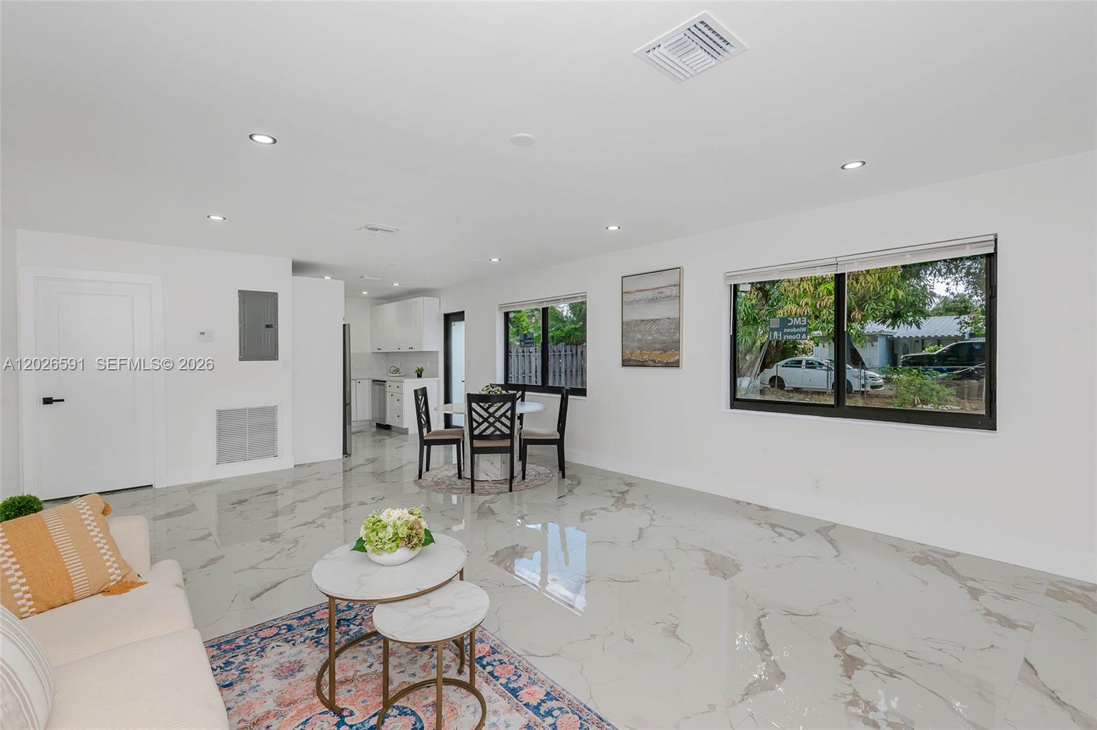 A bright living and dining area features white walls, marble-patterned tile floors, and large windows — 537 S 29th Ct, Hollywood FL 33020, HOLLYWOOD, FL