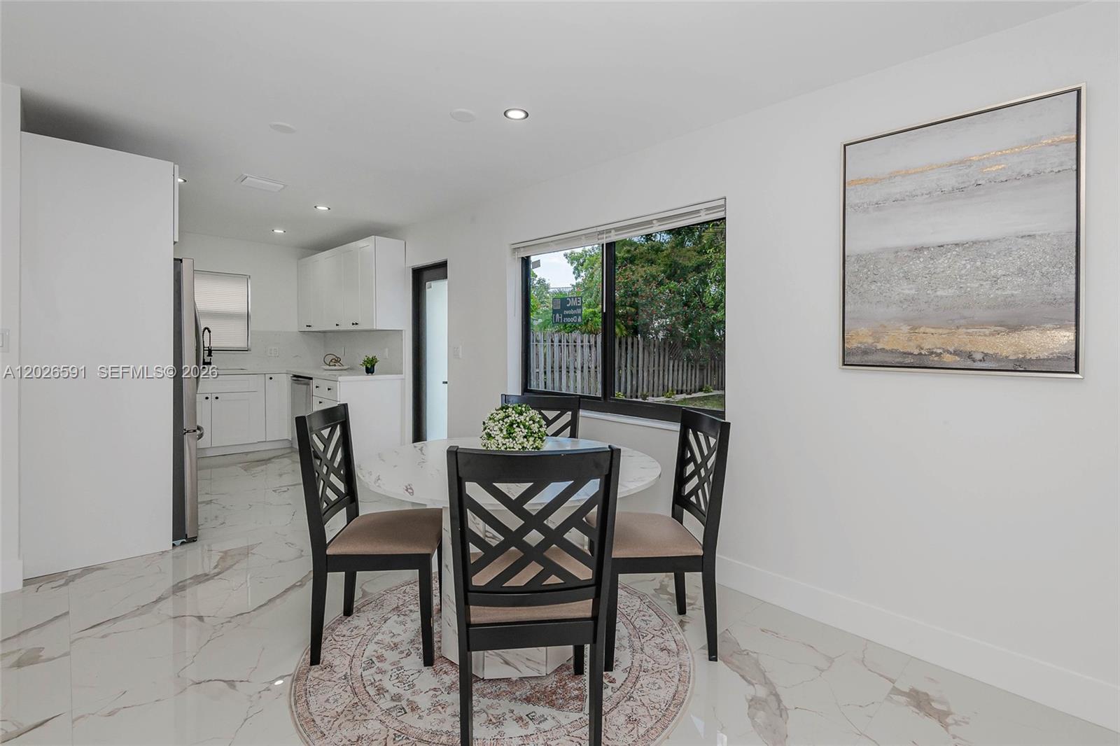 A dining area features a round marble table, four black chairs, and white tile flooring — 537 S 29th Ct, Hollywood FL 33020, HOLLYWOOD, FL