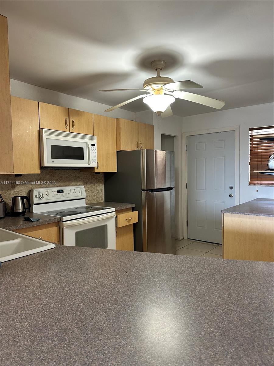 A kitchen features light wood cabinets, stainless steel appliances, and a gray countertop — 1750 NE 191st St # 4, Miami FL 33179, MIAMI, FL