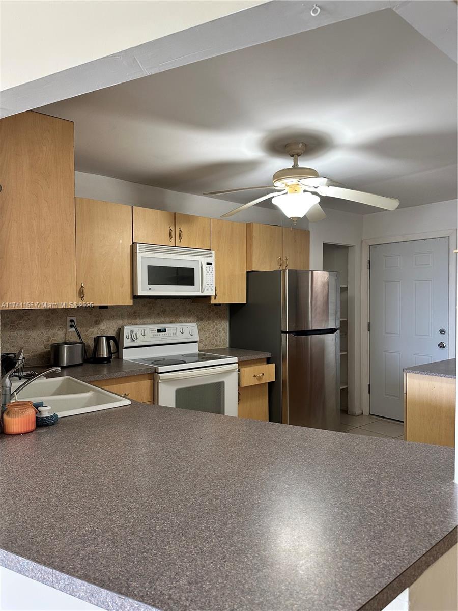 A kitchen features light wood cabinets, stainless steel appliances, and a gray speckled countertop — 1750 NE 191st St # 4, Miami FL 33179, MIAMI, FL