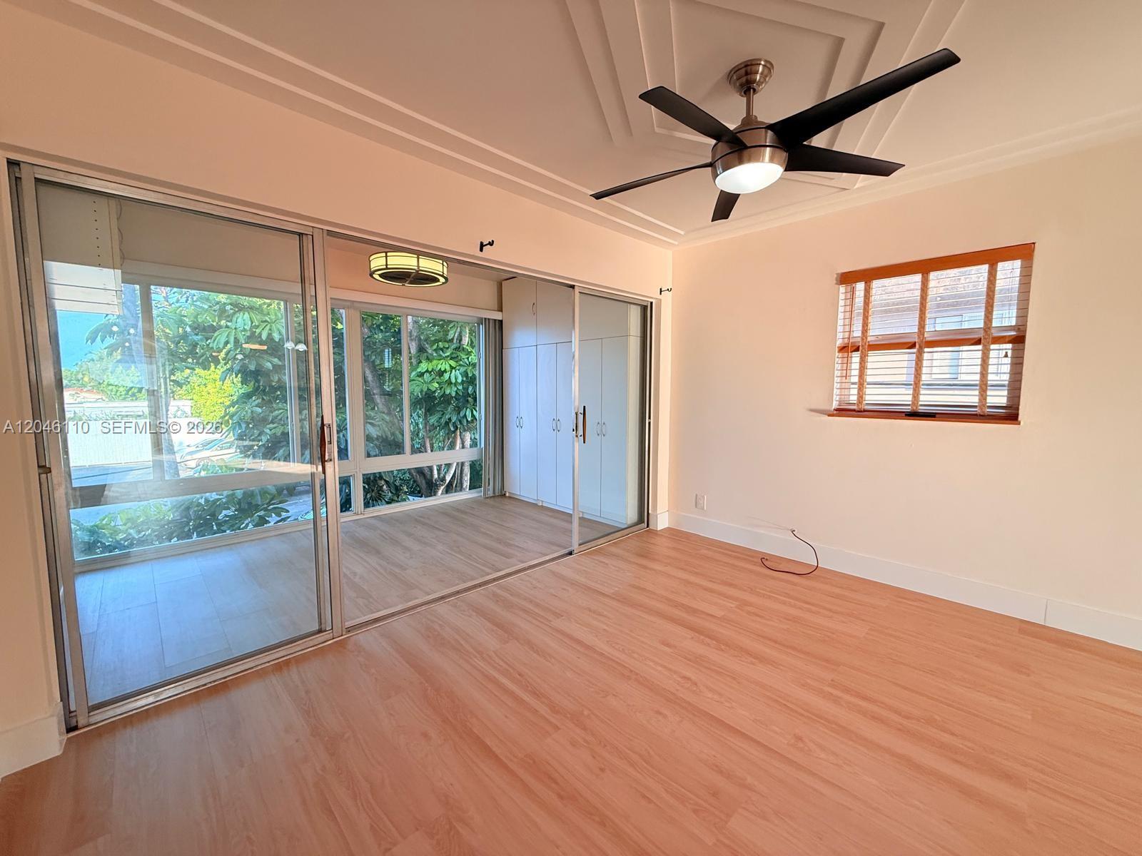 A room with light wood flooring, a ceiling fan, sliding glass doors, and a window — 2832 Fillmore St # 20, Hollywood FL 33020, HOLLYWOOD, FL