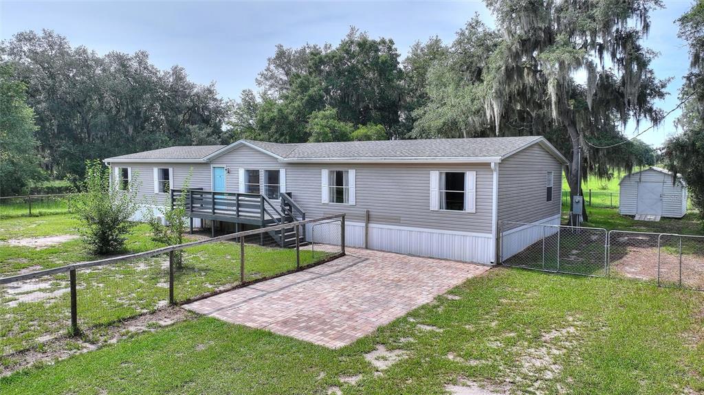 A single-story manufactured home with light siding, a wooden deck, and a brick patio area — 2524 CATFISH COURT, LAKE WALES, FL