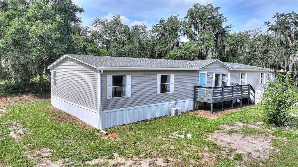 A single-story manufactured home with gray siding, a wooden deck, and a light blue door — 2524 CATFISH COURT, LAKE WALES, FL