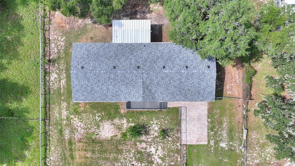 An aerial view shows a house with a gray shingled roof, a metal-roofed patio, and landscaping — 2524 CATFISH COURT, LAKE WALES, FL