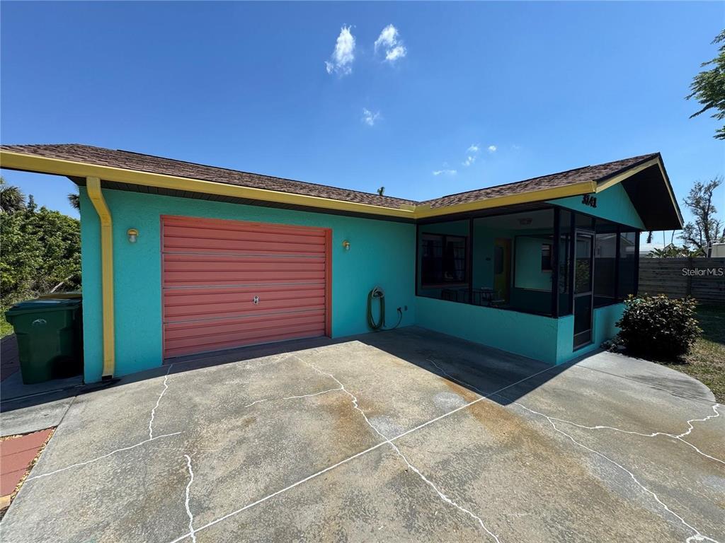 A teal house with a coral garage door and a screened-in porch under a blue sky — 3141 10TH STREET, ENGLEWOOD, FL