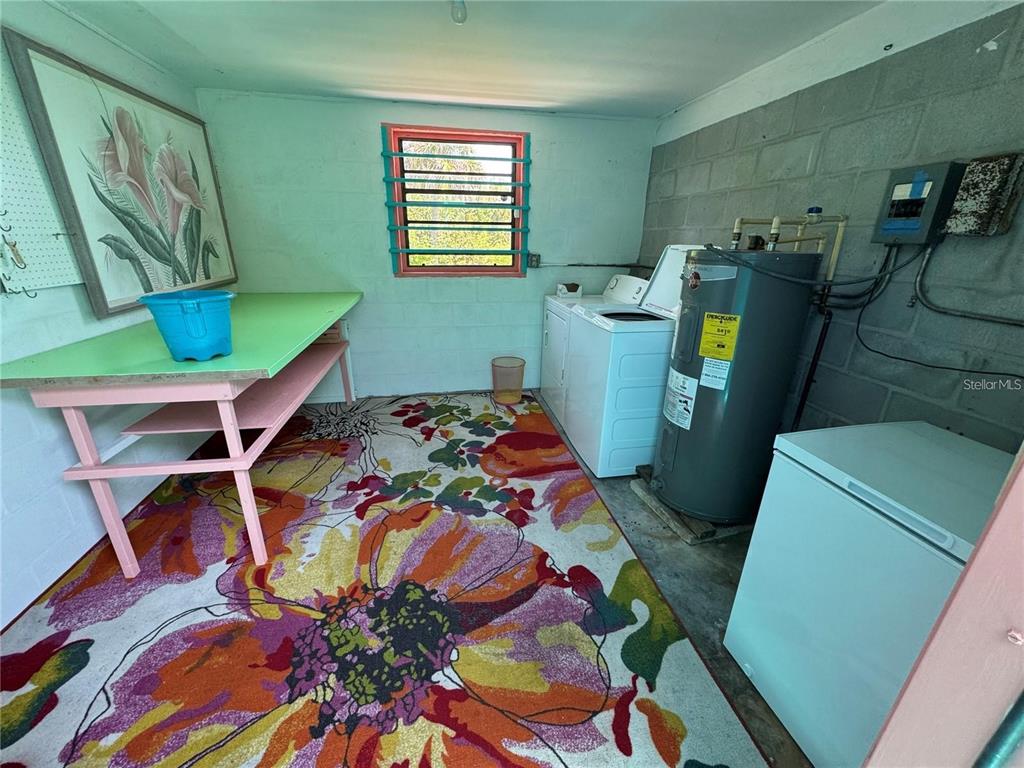 A laundry room features a floral rug, a green table, a water heater, and appliances — 3141 10TH STREET, ENGLEWOOD, FL