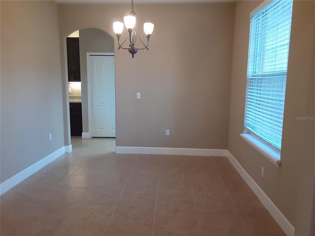 A dining area with tile flooring, a chandelier, and a window with blinds — 33848 EMERALD POND LOOP, LEESBURG, FL
