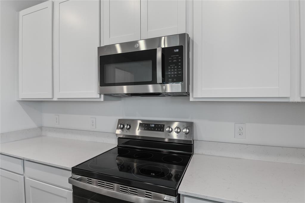 A kitchen features white cabinets, a stainless steel microwave, and a glass-top electric range — 6179 DAPHNE STREET, LAKE HAMILTON, FL