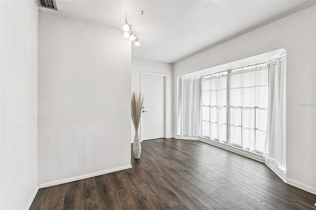 A room with dark wood-look flooring, white walls, a bay window, and a track light — 855 E BRANDON BOULEVARD, BRANDON, FL