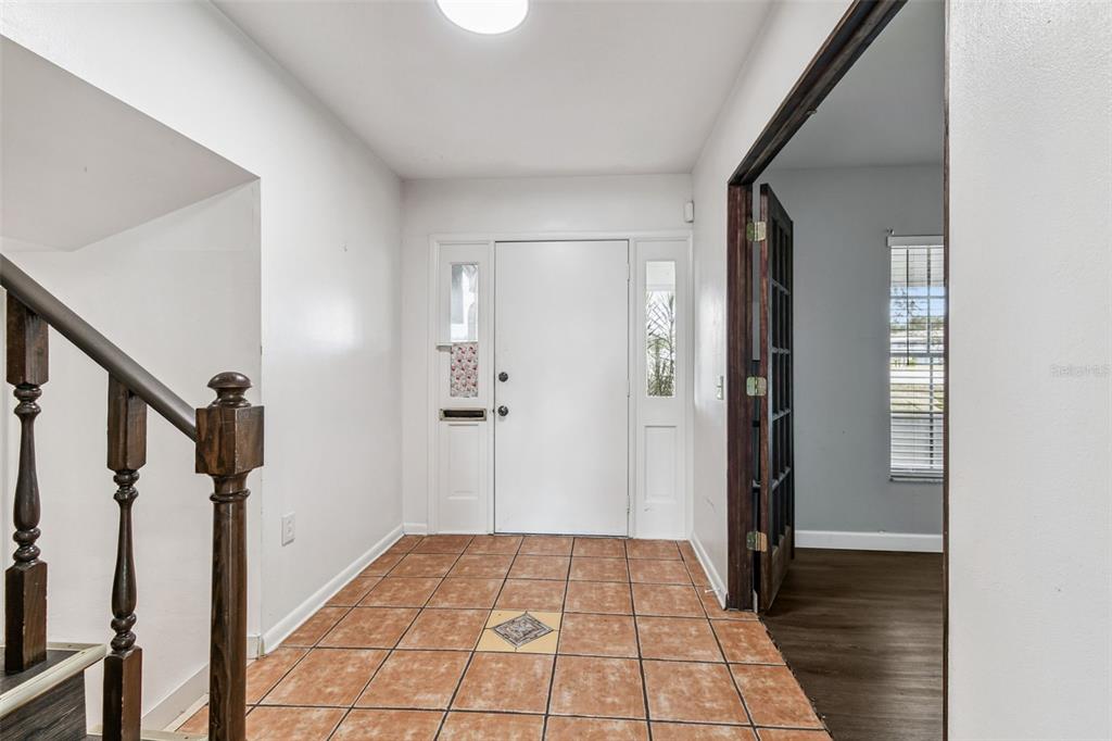 An entryway features tile flooring, a white front door with sidelights, and a wooden staircase — 855 E BRANDON BOULEVARD, BRANDON, FL