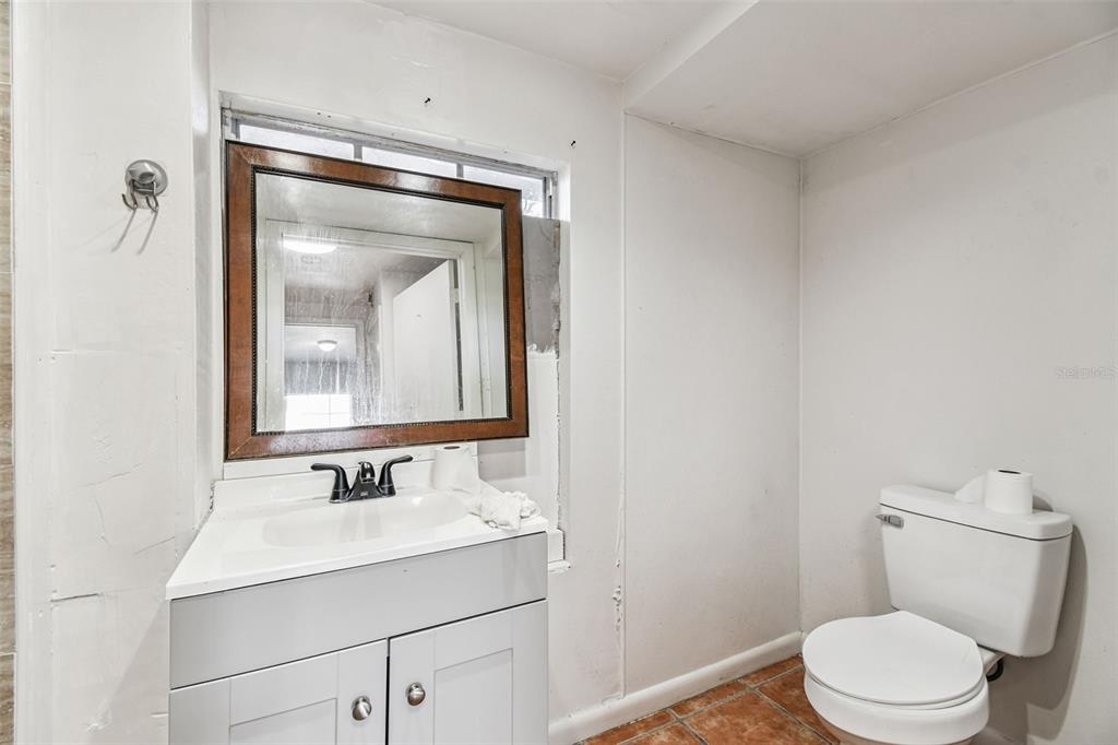 A small bathroom features a white vanity, a framed mirror, and a toilet on tile flooring — 855 E BRANDON BOULEVARD, BRANDON, FL