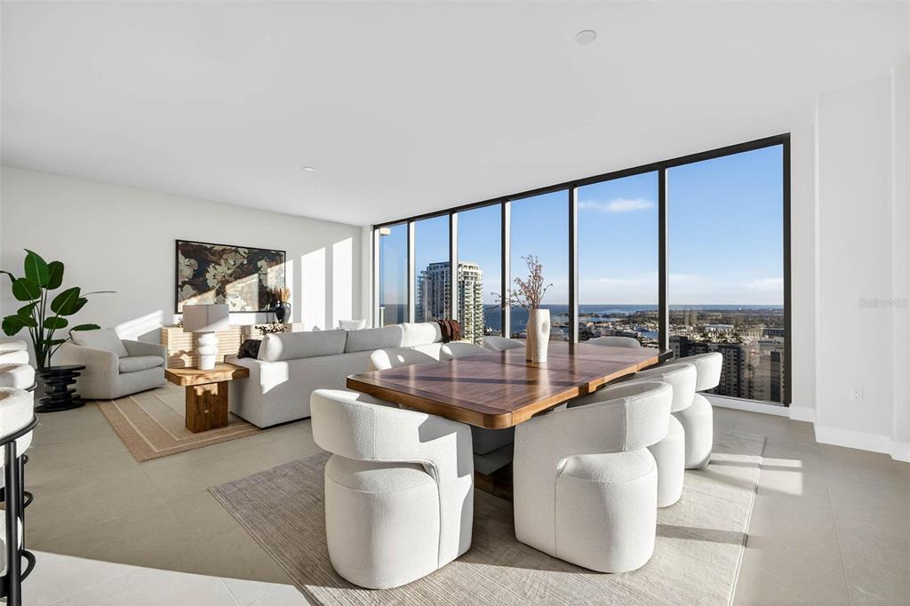 A modern open-concept living and dining area features floor-to-ceiling windows with expansive water views — 275 1ST AVE S UNIT 2706, ST PETERSBURG, FL