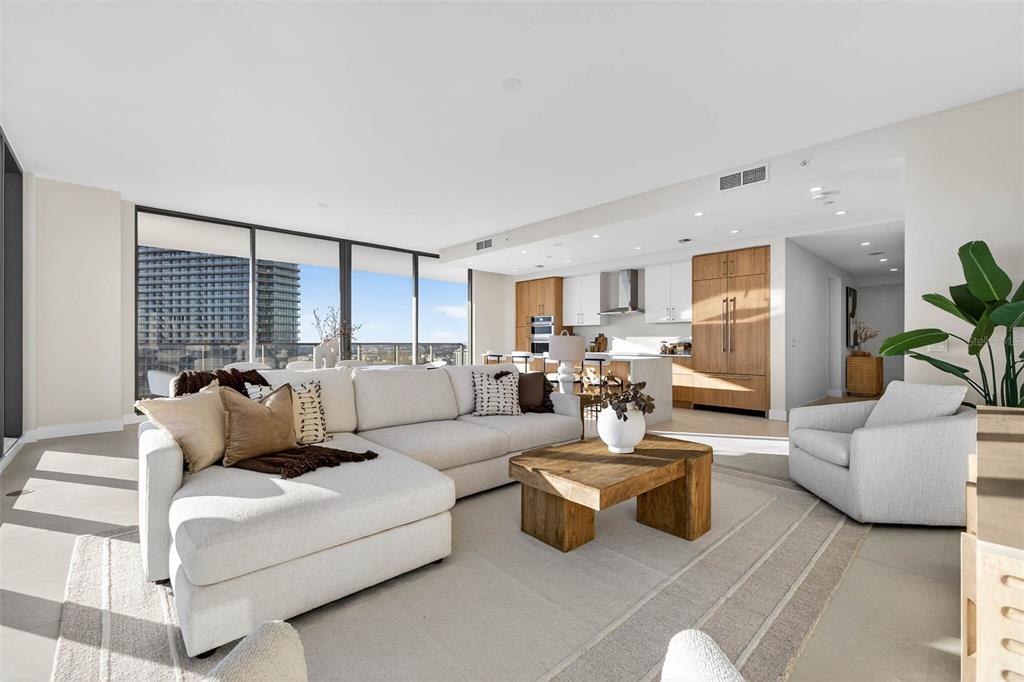 A modern open-concept living room features a large sectional sofa, wood coffee table, and kitchen — 275 1ST AVE S UNIT 2706, ST PETERSBURG, FL