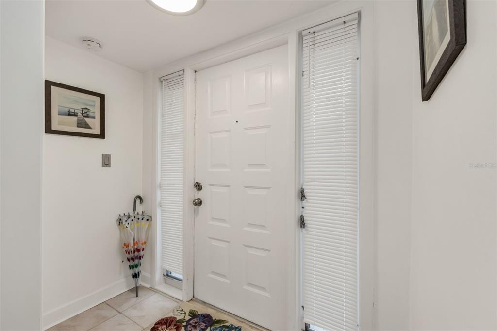 A white front door with sidelights and an umbrella stand in a tiled entryway — 311 GARVIN STREET UNIT 205A, PUNTA GORDA, FL