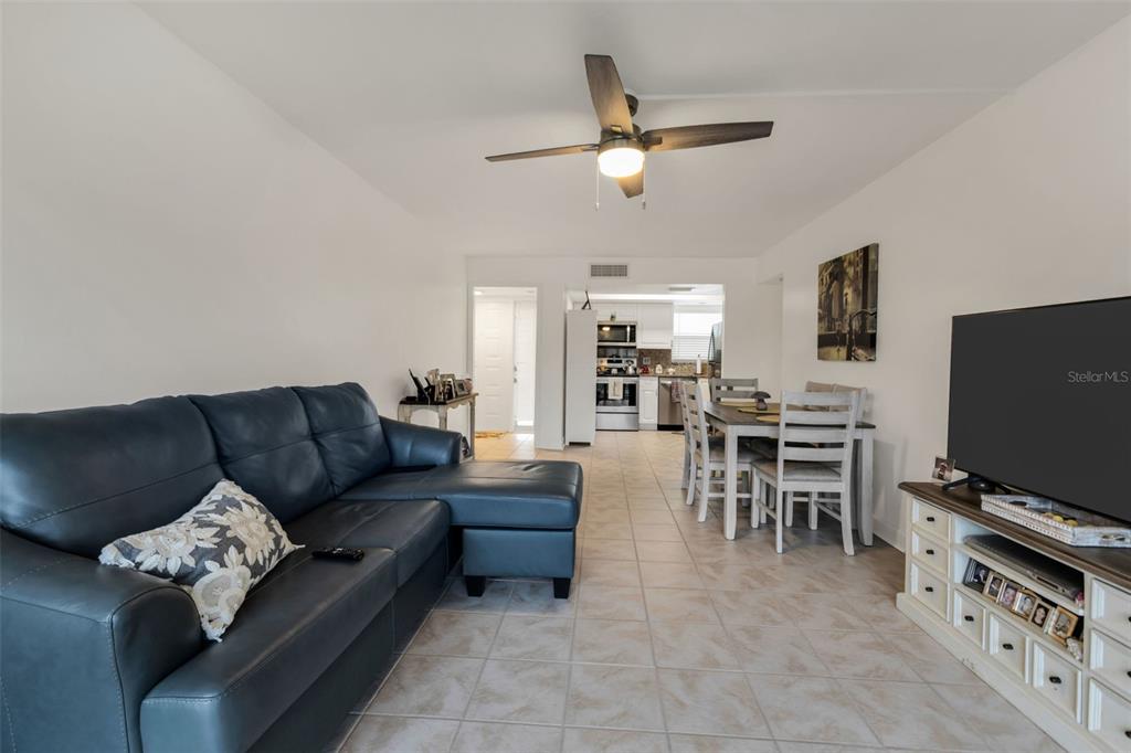 A living room with a blue sectional sofa, dining area, and tile flooring — 311 GARVIN STREET UNIT 205A, PUNTA GORDA, FL