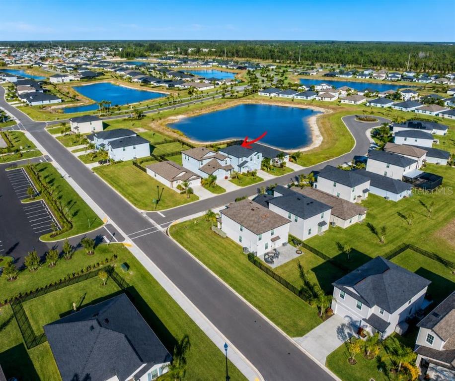 An aerial view shows a suburban neighborhood with houses surrounding a large retention pond — 17809 BELFORTE COURT, NORTH FORT MYERS, FL
