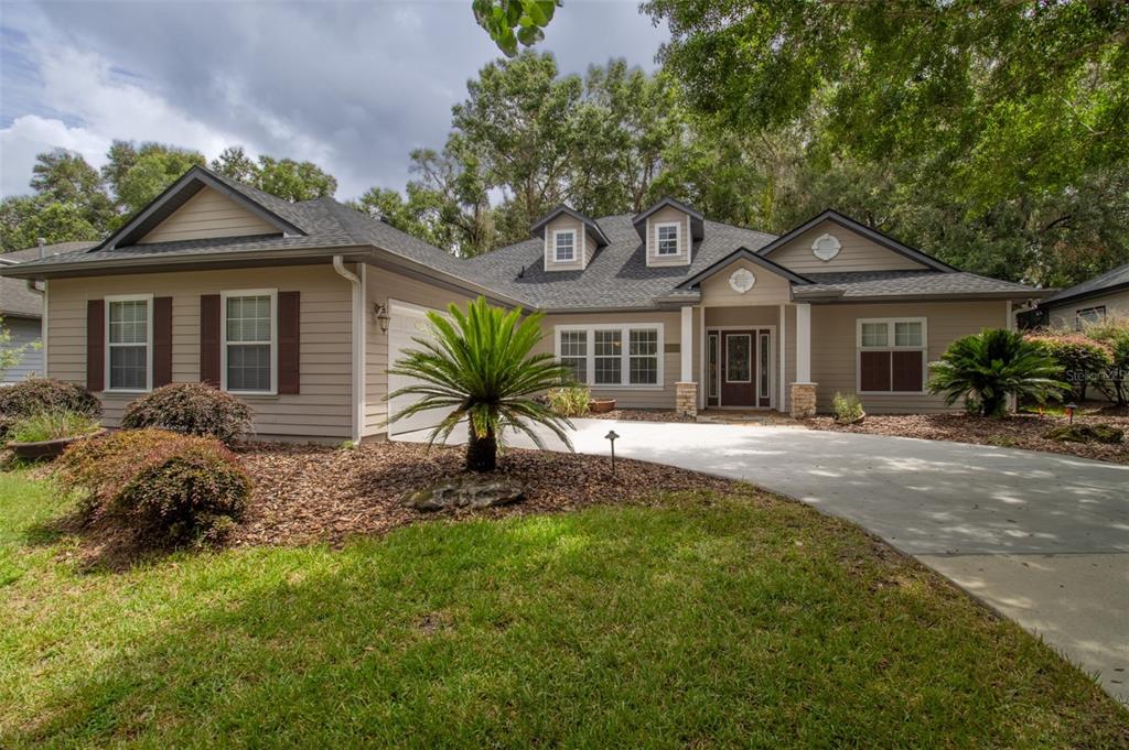 A single-story house with tan siding, a gray shingled roof, and a concrete driveway — 8331 SW 75TH ROAD, GAINESVILLE, FL
