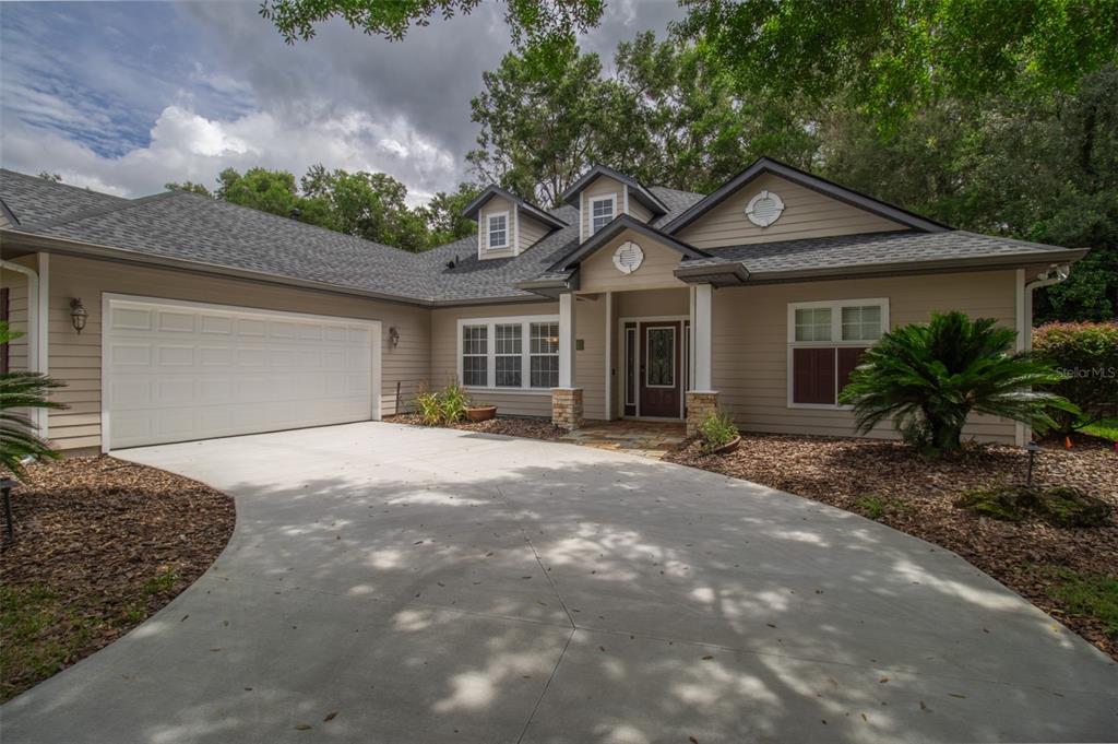 A tan, single-story house with a two-car garage, stone-accented entryway, and a concrete driveway — 8331 SW 75TH ROAD, GAINESVILLE, FL