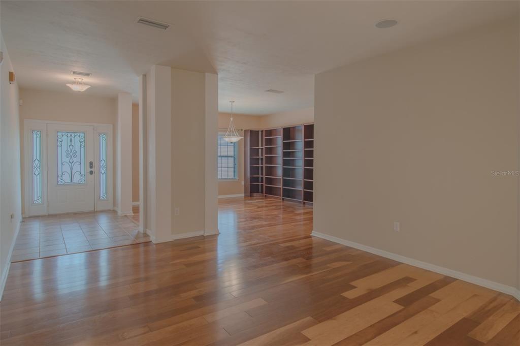 An entryway with tile flooring leads into a living area featuring hardwood floors and bookshelves — 8331 SW 75TH ROAD, GAINESVILLE, FL