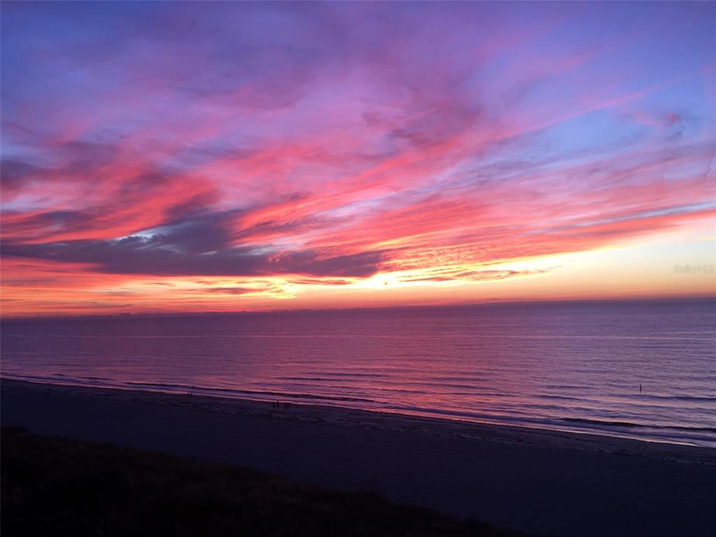 A vibrant sunset over the ocean viewed from an elevated beachside vantage point — 1380 GULF BOULEVARD UNIT 307, CLEARWATER BEACH, FL
