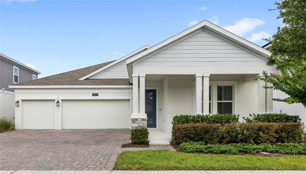 A single-story house with a two-car garage, light siding, and a covered front porch — 3084 ELLA WAY, ST CLOUD, FL