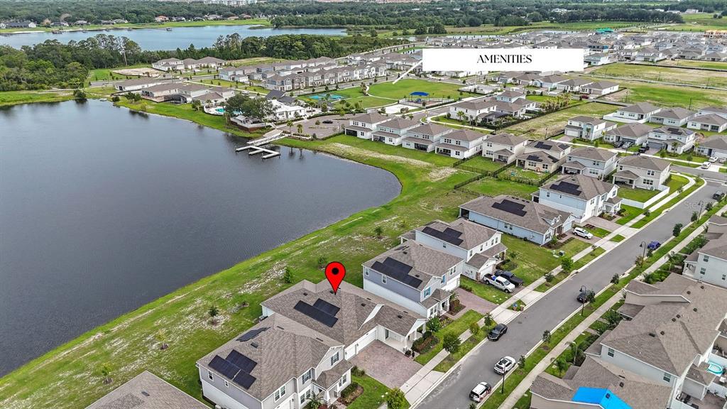 An aerial view shows a residential neighborhood with houses, a lake, and a community amenities area — 3084 ELLA WAY, ST CLOUD, FL
