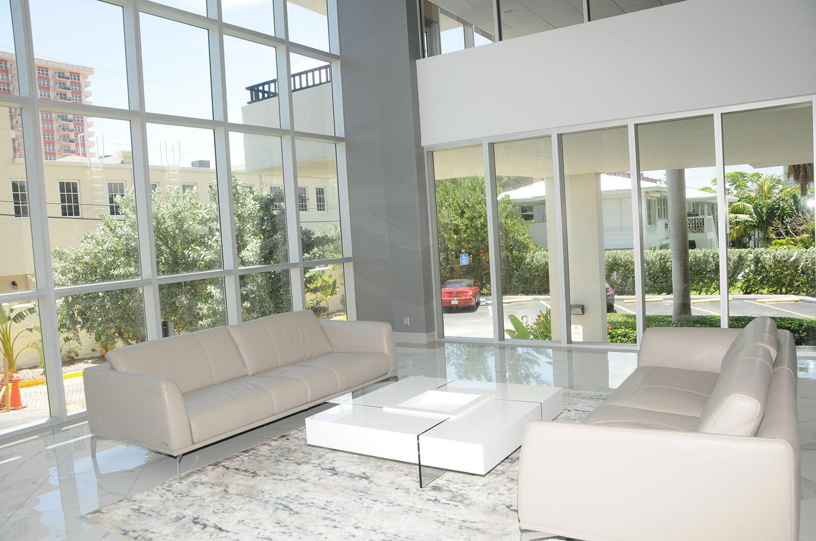 A modern lobby features two beige leather sofas, a white coffee table, and floor-to-ceiling windows — 525 N Ocean Boulevard # 1120, Pompano Beach FL 33062, POMPANO BEACH, FL