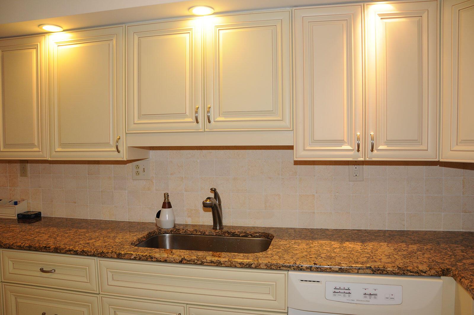 A kitchen sink area with cream cabinets, granite countertops, and a tiled backsplash — 525 N Ocean Boulevard # 1120, Pompano Beach FL 33062, POMPANO BEACH, FL