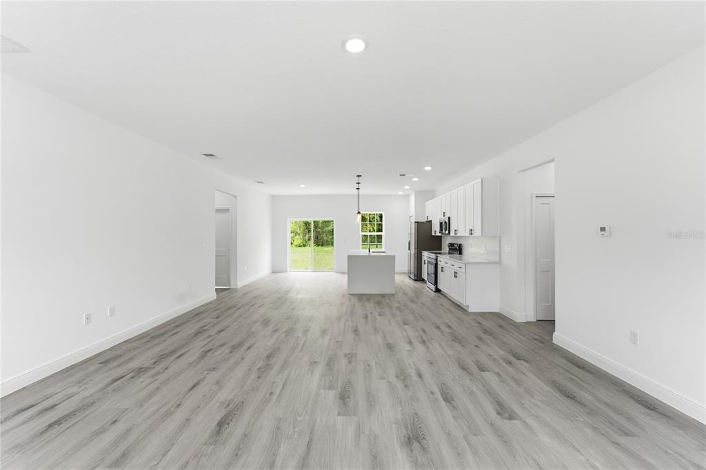 An open-concept kitchen and living area features white cabinetry, a center island, and wood-look flooring — 16390 SW 27TH TERRACE ROAD, OCALA, FL