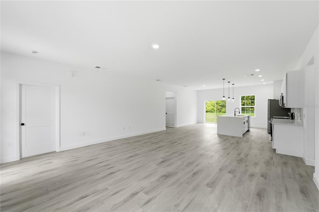 An open-concept kitchen and living area features white cabinetry, a center island, and light-colored flooring — 16390 SW 27TH TERRACE ROAD, OCALA, FL