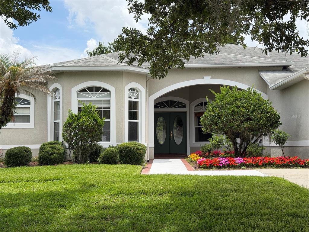 The front exterior of a single-story house features a covered entryway, arched windows, and landscaping — 2734 WINDSORGATE LANE, ORLANDO, FL