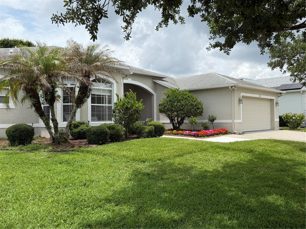 A single-story house with a beige stucco exterior, a two-car garage, and a palm tree — 2734 WINDSORGATE LANE, ORLANDO, FL