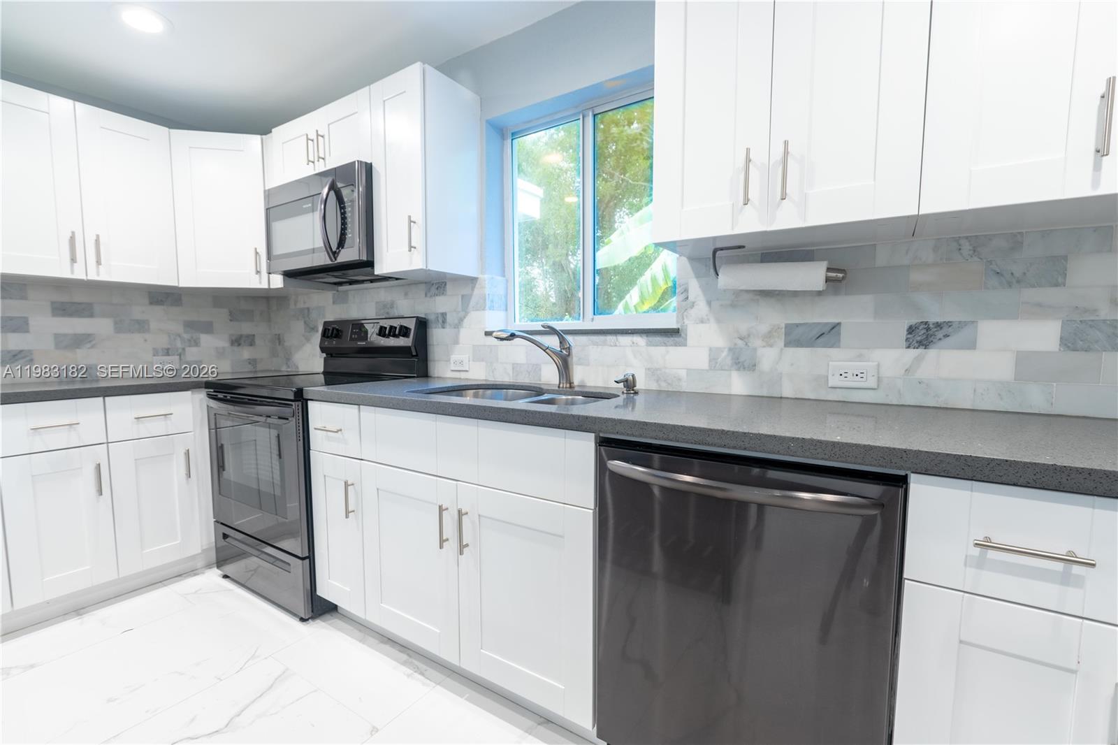 A kitchen features white cabinets, dark countertops, stainless steel appliances, and a tiled backsplash — 11 Judy Pl, Key Largo FL 33037, KEY LARGO, FL