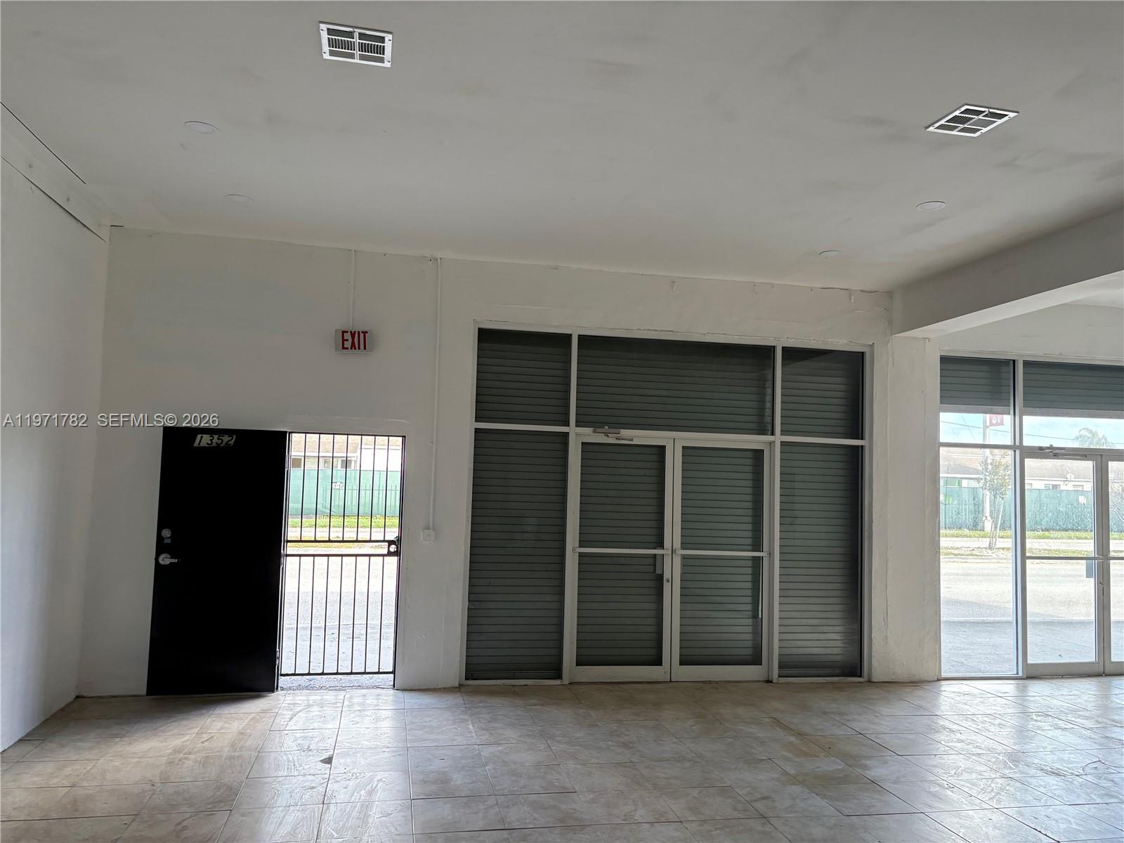 An empty commercial space features tiled floors, white walls, and large glass storefront windows — 1350 NW 62nd St, Miami FL 33147, MIAMI, FL