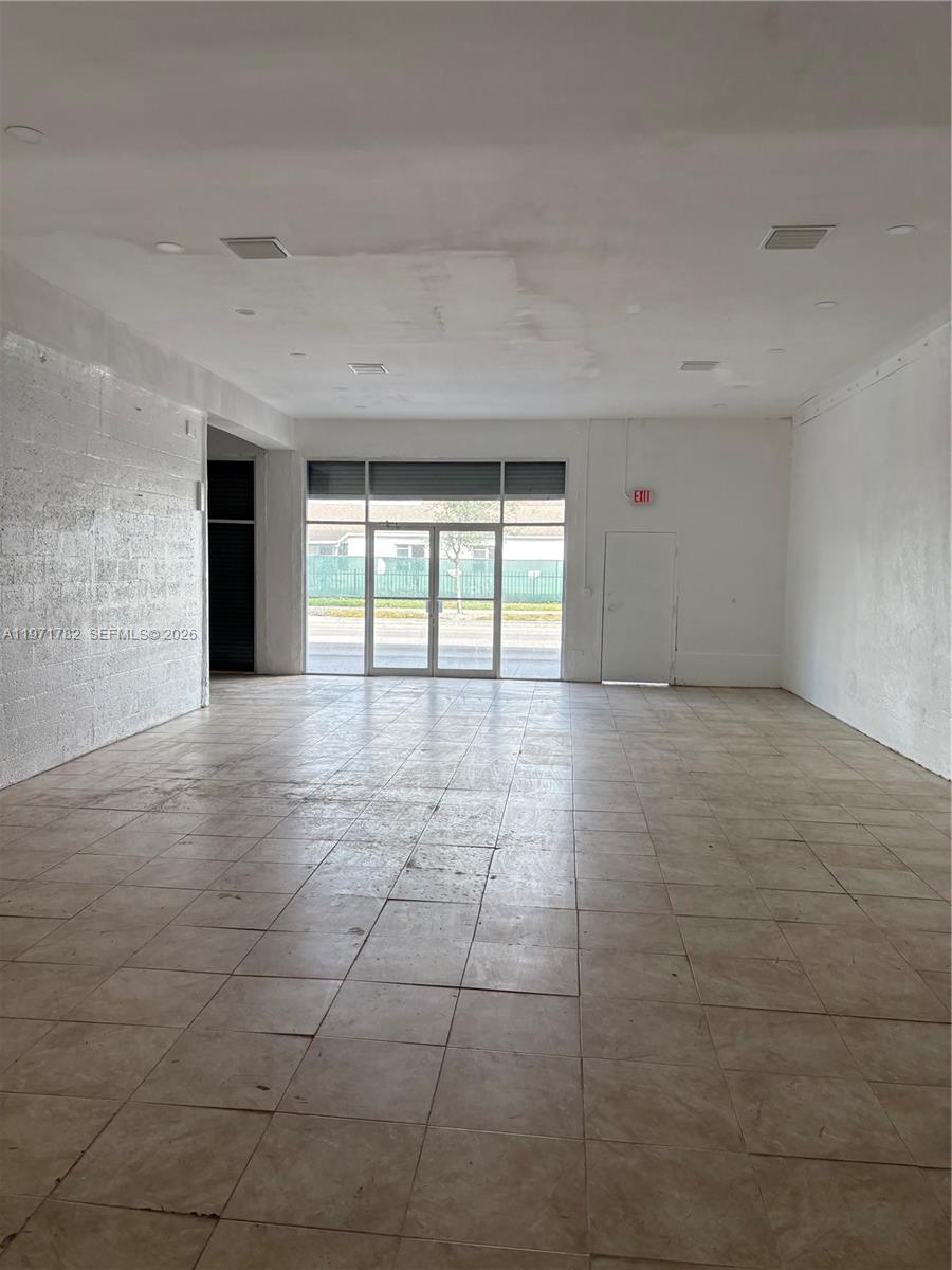 An empty commercial space features white walls, a tiled floor, and a glass storefront entrance — 1350 NW 62nd St, Miami FL 33147, MIAMI, FL