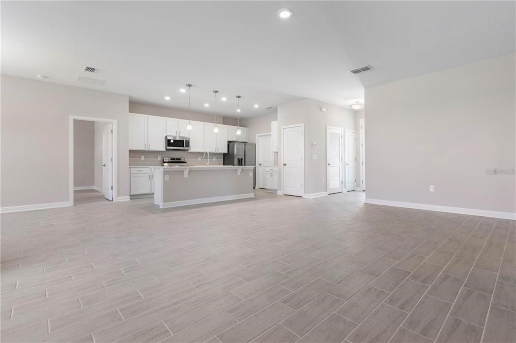 An open-concept kitchen with white cabinets and a breakfast bar overlooks a tiled living area — 2235 SATURDAY STREET, NORTH PORT, FL