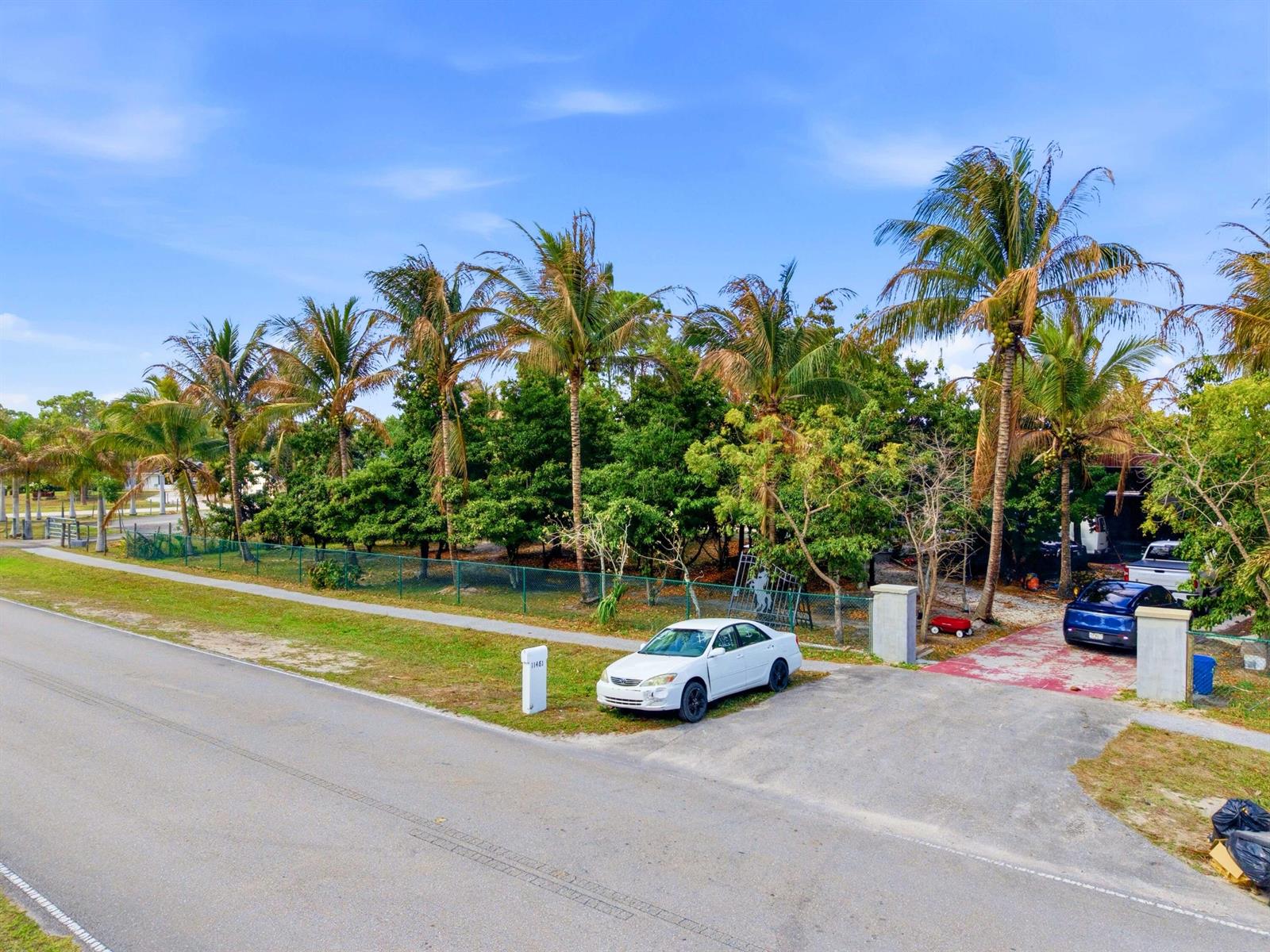 A white car is parked in the driveway of a property with palm trees — 11481 Tangerine Boulevard, FL 33412, FL