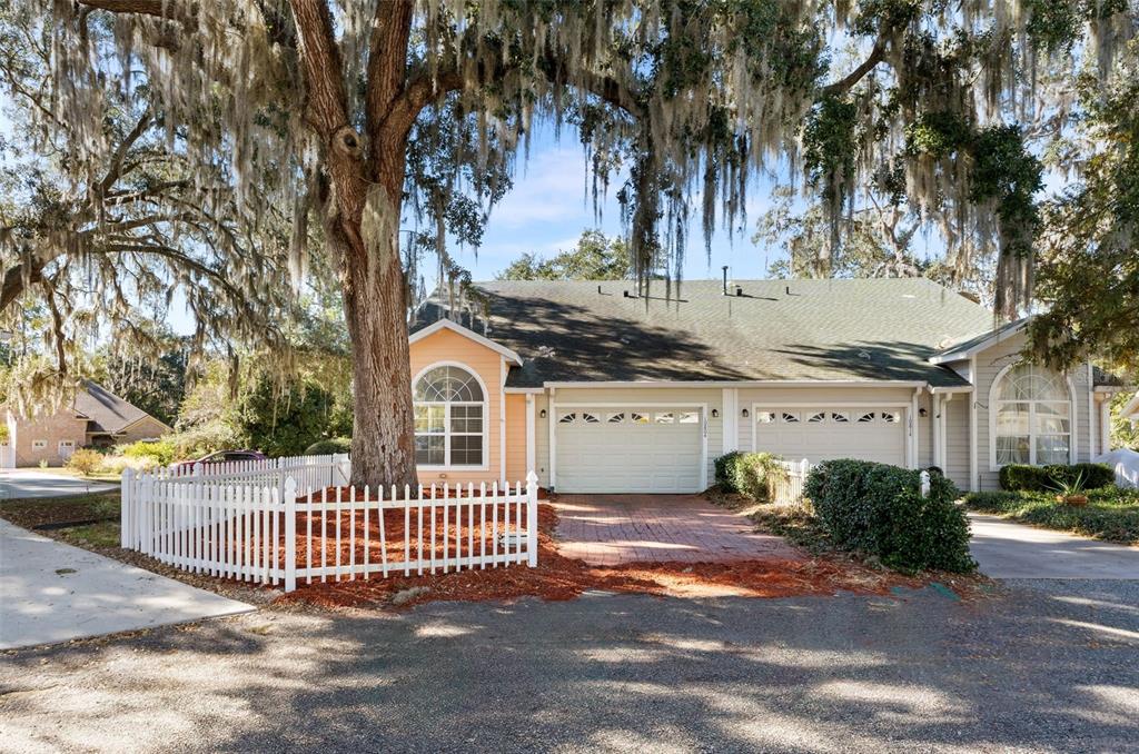 A duplex home with two garage doors, a fenced tree, and hanging Spanish moss — 10804 NW 65TH WAY, ALACHUA, FL