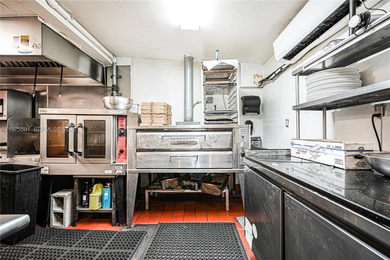 A commercial kitchen features stainless steel ovens, a prep counter, and shelving on tiled floors — 2426 NE 2nd Ave, Miami FL 33137, MIAMI, FL
