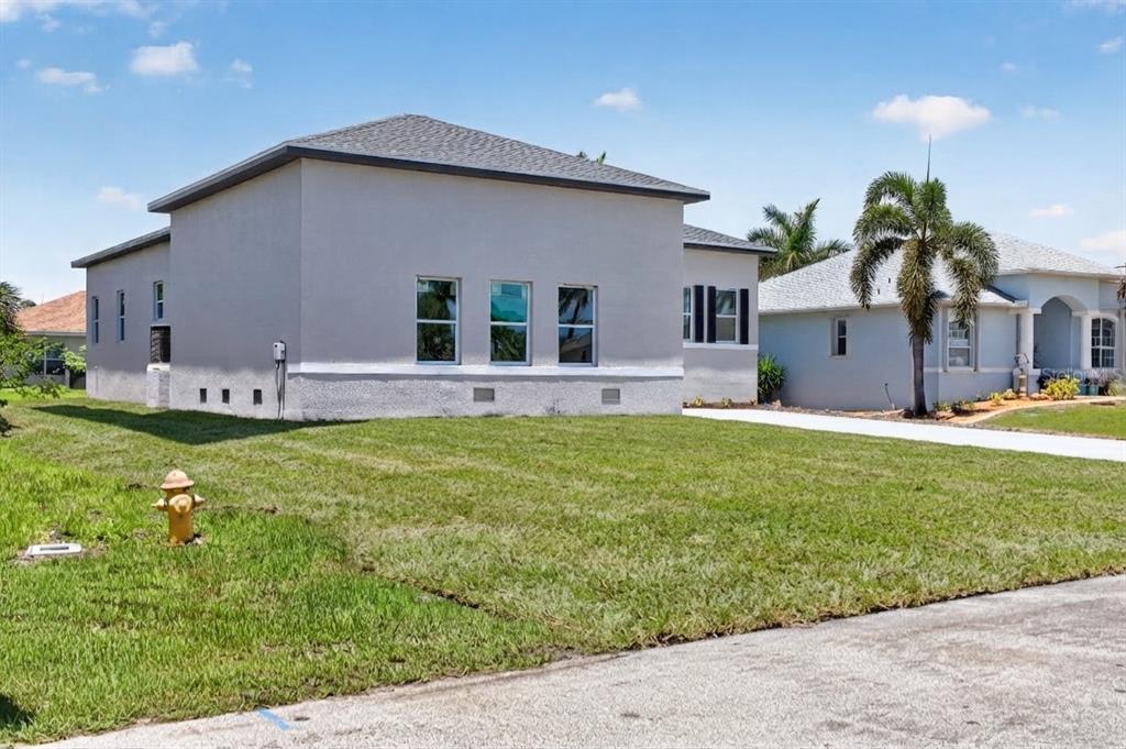 A side view of a light-colored, single-story house with a lawn and a fire hydrant — 15809 MELPORT CIRCLE, PORT CHARLOTTE, FL
