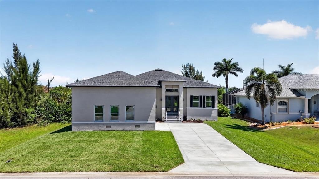 A single-story house with a gray stucco exterior, a concrete driveway, and a front entrance — 15809 MELPORT CIRCLE, PORT CHARLOTTE, FL
