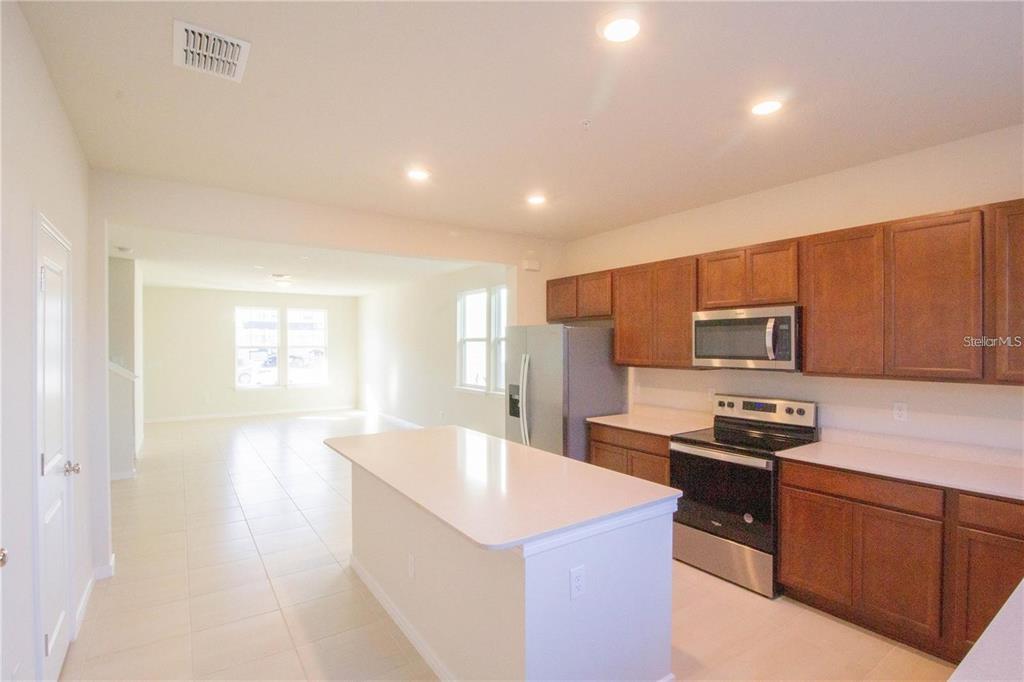 A kitchen with wood cabinets, stainless steel appliances, and a white island — 10355 FOLLY BEACH ROAD, ORLANDO, FL